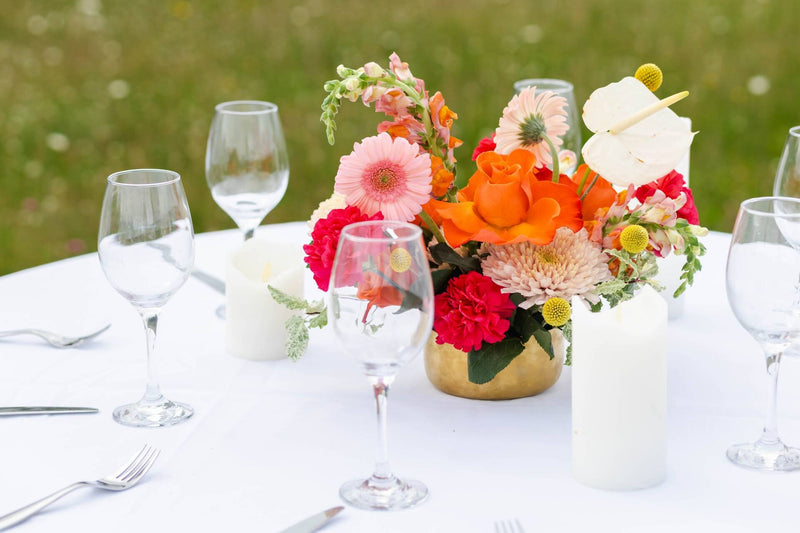Decorative table setting with a floral centerpiece and wine glasses on a white tablecloth for wedding in Moncton, by wedding florist Primavera floral Studio in Moncton.