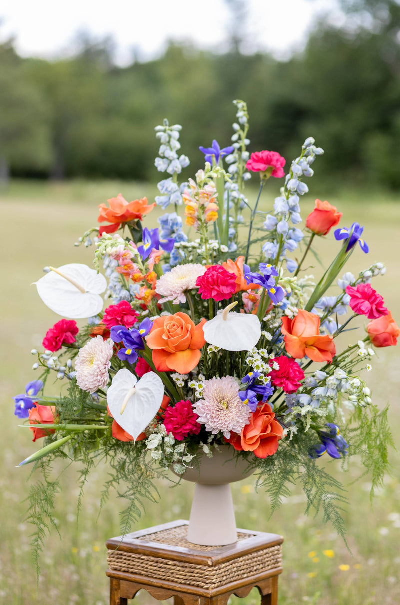Colorful flower arrangement on a pedestal in a natural setting with trees in the background for wedding in new brunswick