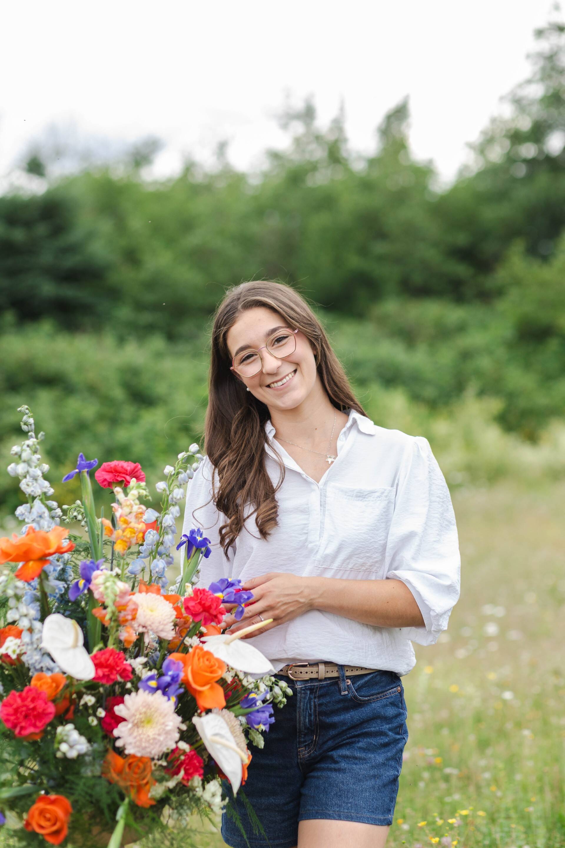 Julie Losier from Primavera Floral studio holding a bouquet of flowers in a field
