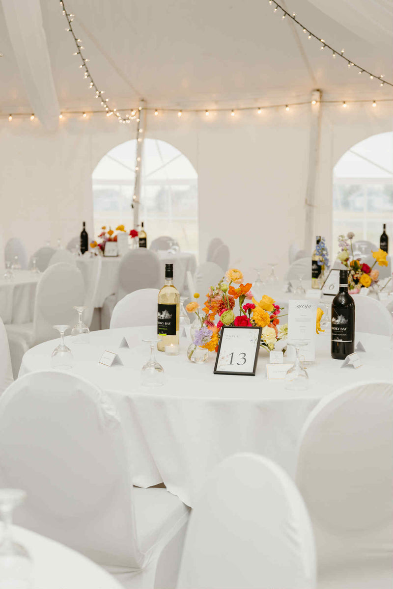 Decorated wedding reception with tables, chairs, and floral centerpieces under a white tent. WEdding florist Primavera Floral studio in Moncton made the floral decoration. Wedding Vendors in New Brunswick.