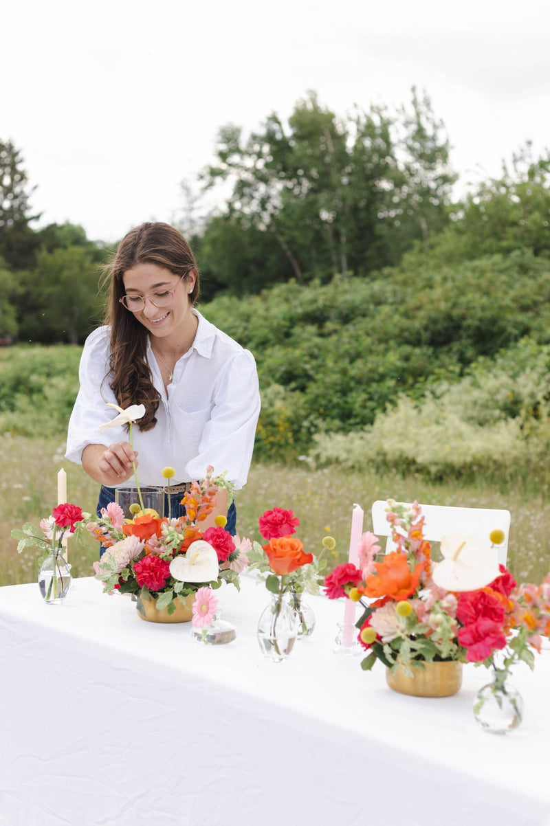 Primavera floral studio arranging wedding flowers outdoors on a sweetheart wedding table with a natural background. Flowers arranged in New Brunswick Canada.
